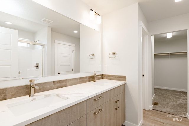 bathroom featuring a sink, visible vents, a stall shower, and double vanity