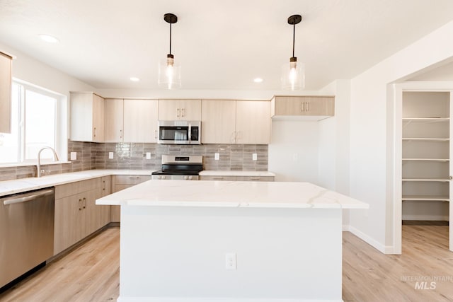 kitchen with a sink, a center island, light brown cabinetry, and stainless steel appliances