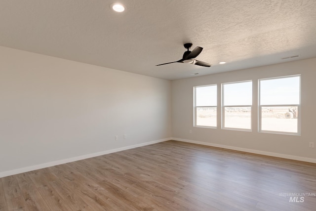 spare room featuring baseboards, light wood-type flooring, and ceiling fan