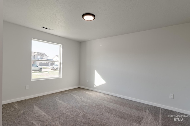 unfurnished room featuring visible vents, baseboards, carpet, and a textured ceiling