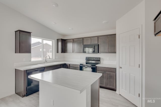 kitchen featuring a center island, vaulted ceiling, light countertops, black appliances, and a sink