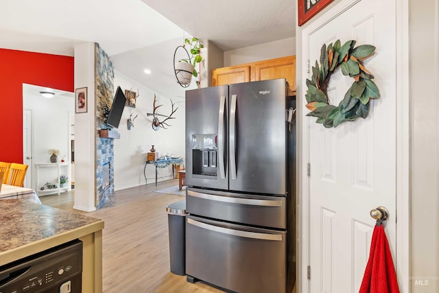 kitchen with black dishwasher, stainless steel refrigerator with ice dispenser, light wood finished floors, dark countertops, and light brown cabinets