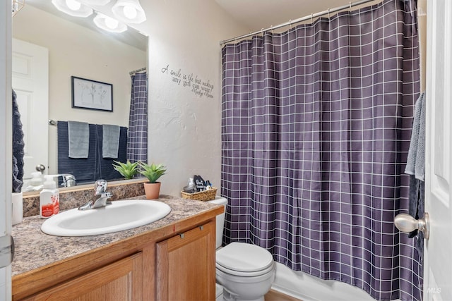 full bath featuring a textured wall, vanity, and toilet