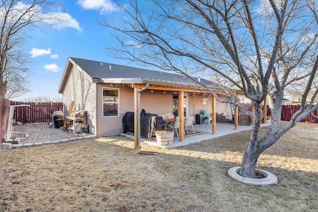 back of property with a patio area, a fenced backyard, a lawn, and roof with shingles