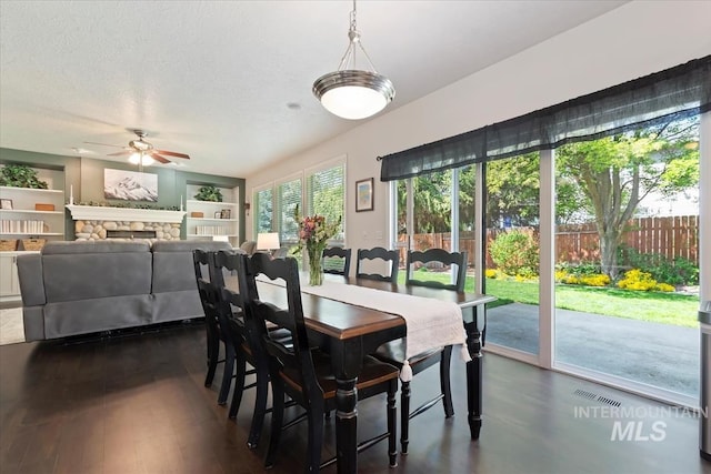 dining space featuring dark wood-style flooring, ceiling fan, visible vents, and built in shelves