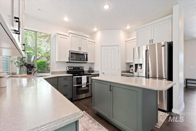 kitchen with a kitchen island, a sink, light countertops, stainless steel appliances, and recessed lighting