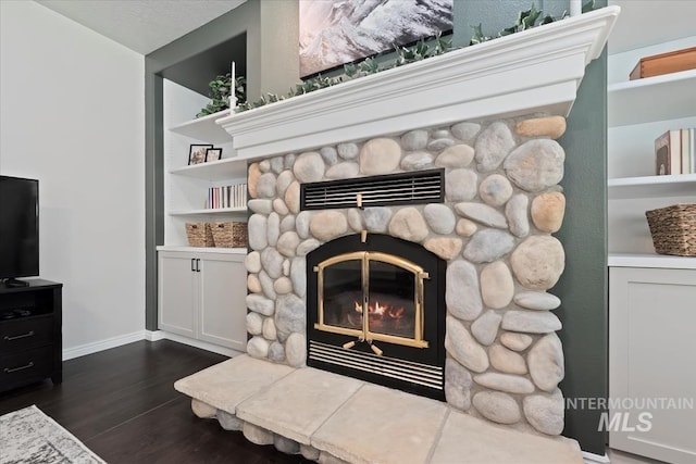 room details featuring baseboards, wood finished floors, and a fireplace