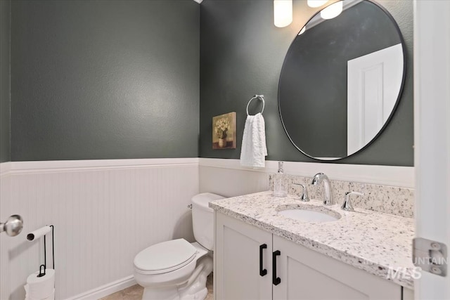bathroom featuring vanity, wainscoting, and toilet