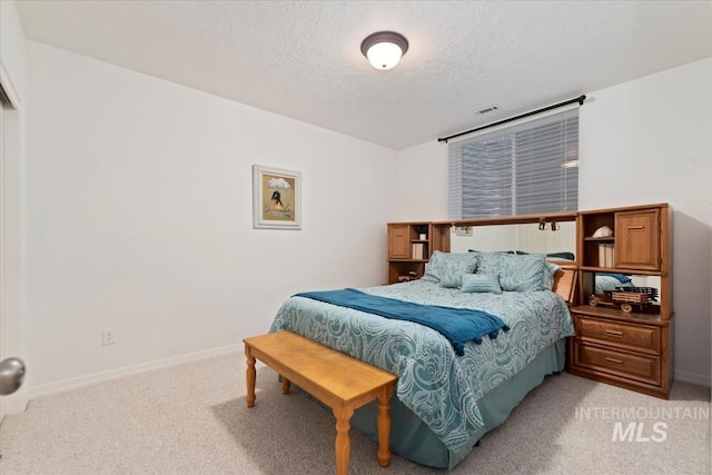 bedroom with a textured ceiling, light colored carpet, baseboards, and visible vents