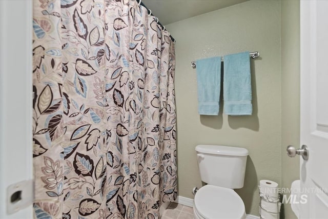 bathroom with baseboards, tile patterned flooring, a shower with curtain, and toilet