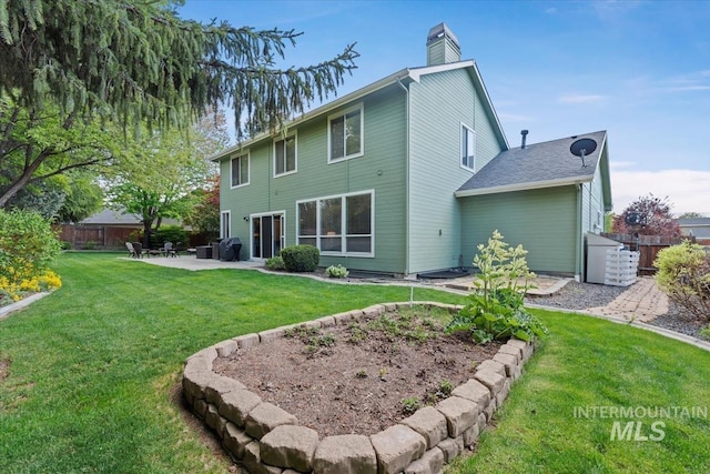 back of property featuring a yard, a patio, fence, and a chimney