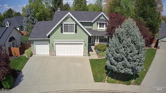 traditional-style home with concrete driveway, roof with shingles, fence, and stone siding
