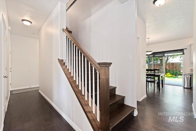 stairway with baseboards, a textured ceiling, and wood finished floors