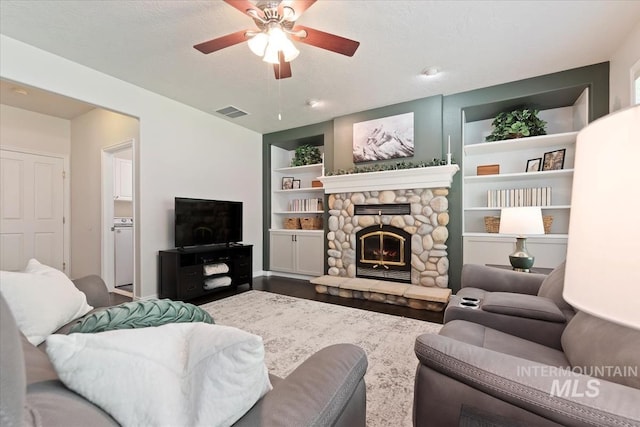 living room with ceiling fan, a fireplace, built in features, washer / clothes dryer, and visible vents