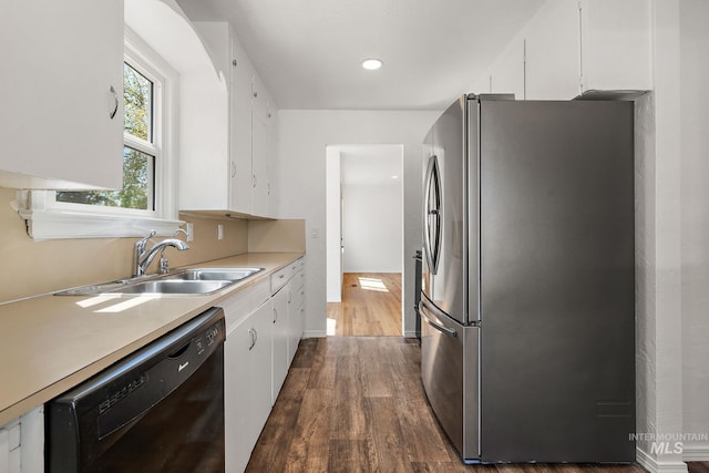 kitchen with freestanding refrigerator, white cabinets, a sink, and black dishwasher