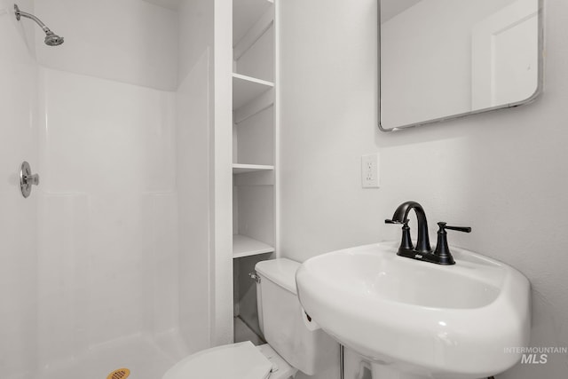 full bathroom featuring a sink, a stall shower, and toilet