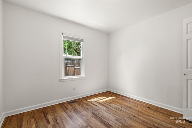 unfurnished room featuring visible vents, baseboards, and wood finished floors