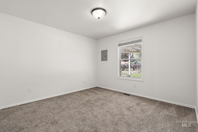 carpeted spare room with baseboards, electric panel, and visible vents