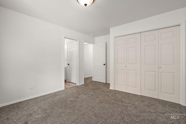 unfurnished bedroom with carpet flooring, baseboards, and a closet
