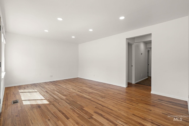 empty room with visible vents, recessed lighting, baseboards, and wood finished floors