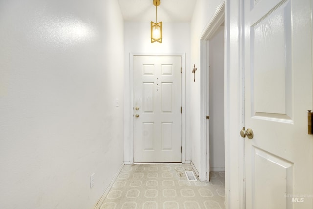 doorway featuring light floors and baseboards