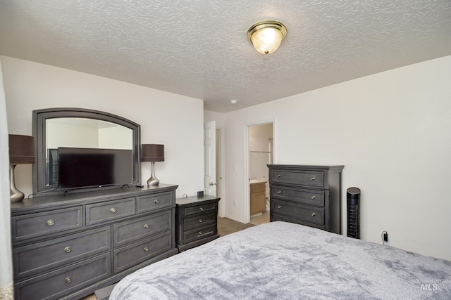 carpeted bedroom with a textured ceiling and ensuite bathroom