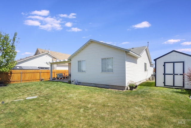 rear view of house with fence, a lawn, an outdoor structure, and a shed