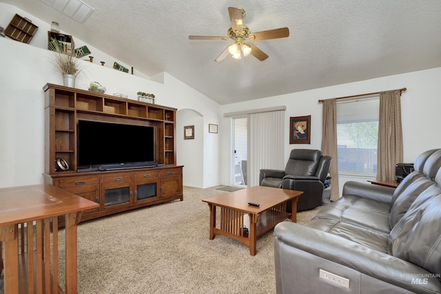 living room with vaulted ceiling, a textured ceiling, ceiling fan, arched walkways, and light carpet