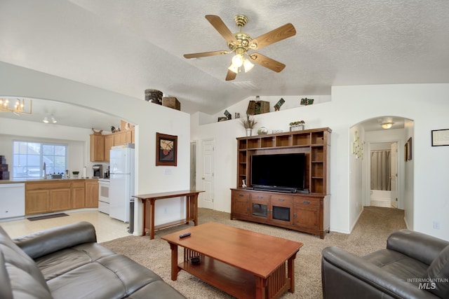 living area with lofted ceiling, arched walkways, a textured ceiling, and ceiling fan