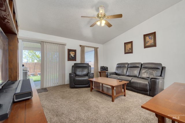 carpeted living area with lofted ceiling, a ceiling fan, and a textured ceiling