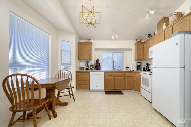 kitchen with a sink, a chandelier, lofted ceiling, white appliances, and light floors