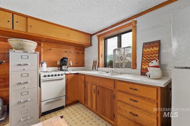 kitchen featuring sink, a textured ceiling, electric range, wooden walls, and kitchen peninsula