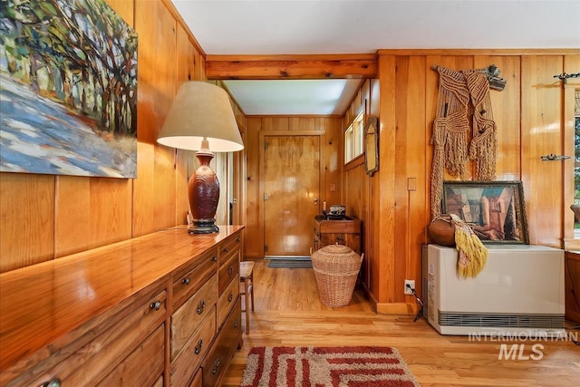 interior space featuring beam ceiling, light hardwood / wood-style flooring, and wood walls