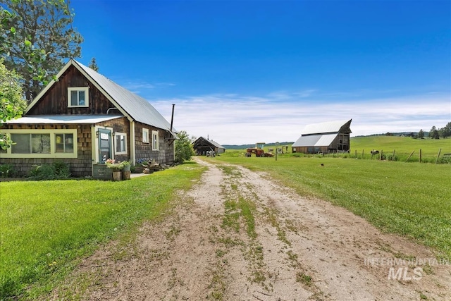 view of property exterior with a lawn and a rural view