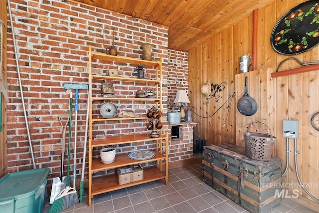 misc room with brick wall, dark tile patterned flooring, wood ceiling, and wood walls