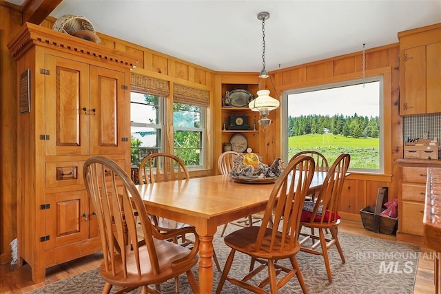 dining space with wooden walls and hardwood / wood-style floors