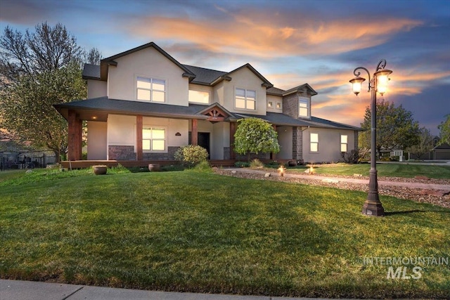view of front of house featuring a lawn, stucco siding, stone siding, and a porch