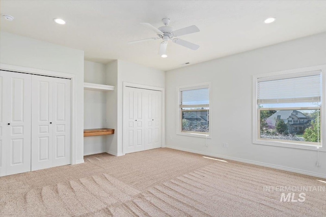 unfurnished bedroom featuring two closets, recessed lighting, baseboards, and carpet floors