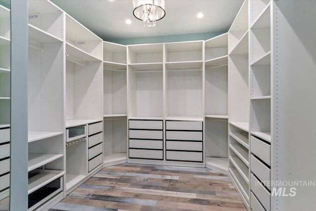 spacious closet featuring an inviting chandelier and wood finished floors