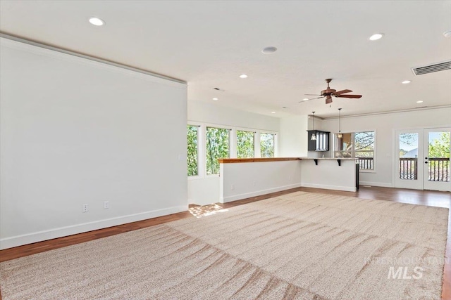 unfurnished living room with visible vents, baseboards, wood finished floors, and a wealth of natural light