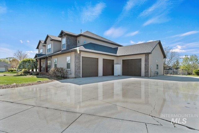 view of side of home with an attached garage, driveway, stone siding, and stucco siding