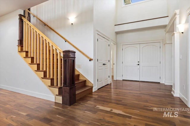 entryway with baseboards, a high ceiling, and wood finished floors
