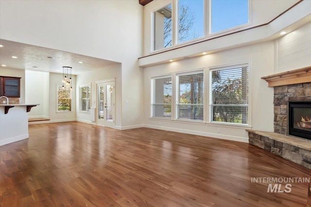 unfurnished living room featuring baseboards, a high ceiling, a fireplace, and wood finished floors