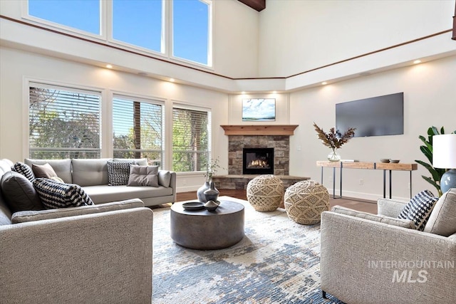 living room featuring baseboards, a fireplace, wood finished floors, and a towering ceiling