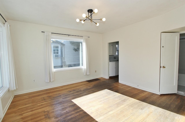 spare room with dark wood-type flooring and a notable chandelier