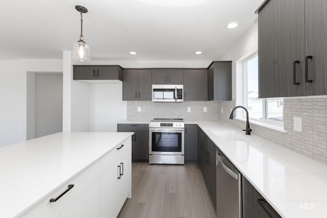 206 Marble Ave, Caldwell, ID 83605 - kitchen with appliances with stainless steel finishes, a sink, light wood finished floors, light countertops, and decorative light fixtures