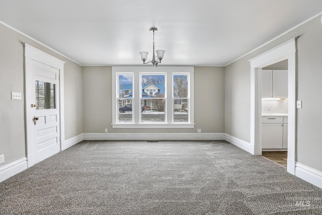 unfurnished dining area featuring carpet floors, ornamental molding, and a notable chandelier