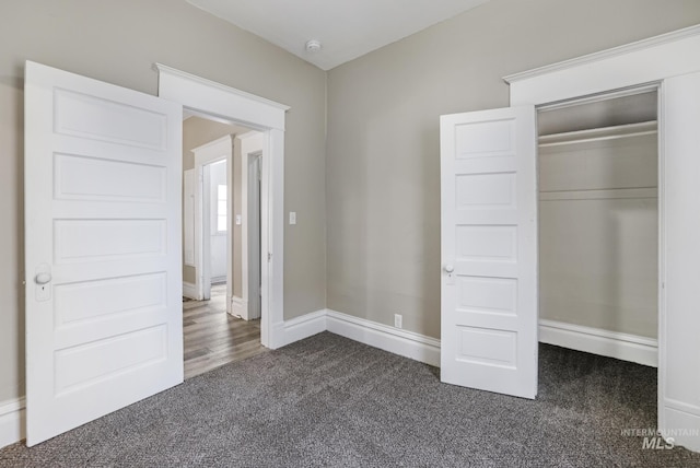 unfurnished bedroom featuring dark carpet and a closet