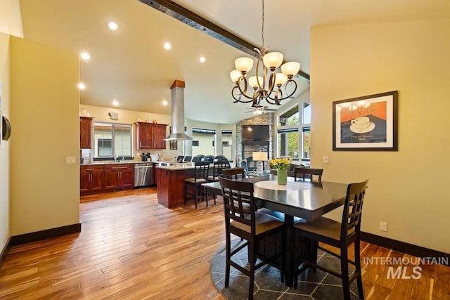 dining area with wood-type flooring, high vaulted ceiling, and a notable chandelier