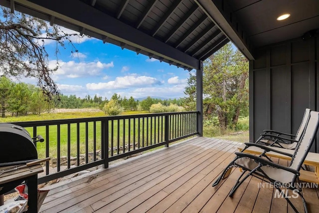 wooden terrace featuring a grill and a yard